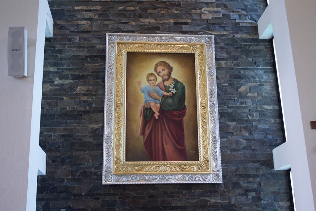 Cuadro de San José con el Niño Jesús sobre muro de piedra