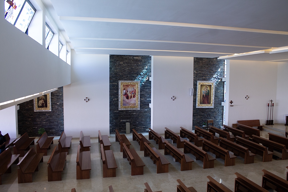 Interior del templo con muros de piedra y cuadros sacros